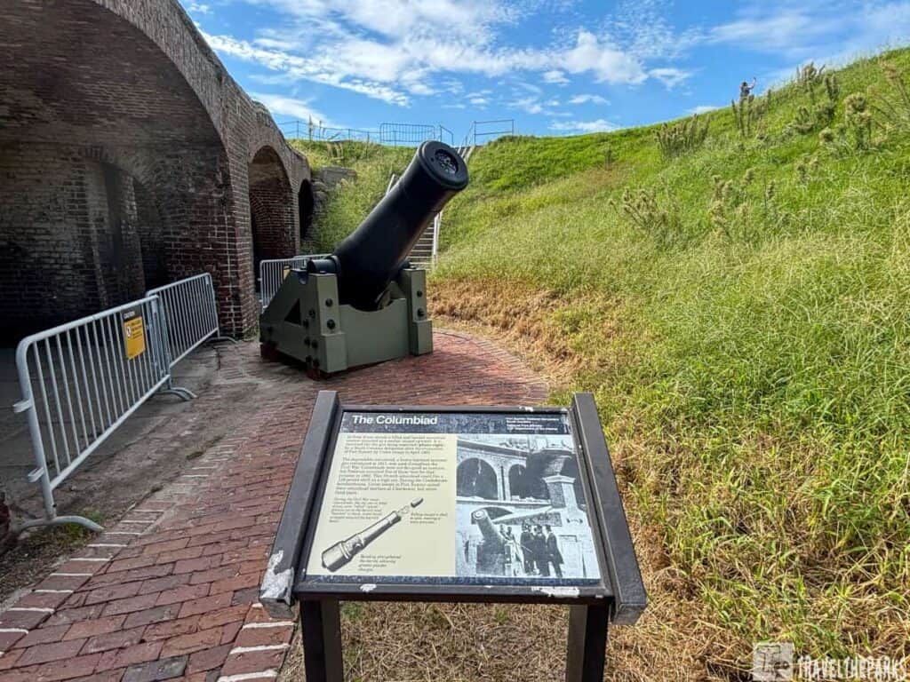 A historic cannon on display at Fort Sumter National Monument with an information plaque "The Columbiad" in the foreground.