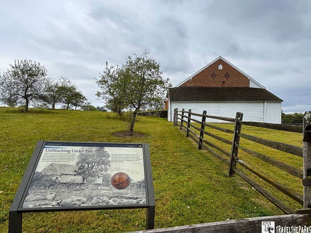 Historical Trostle barn with a cannonball hole and an informational sign in front.