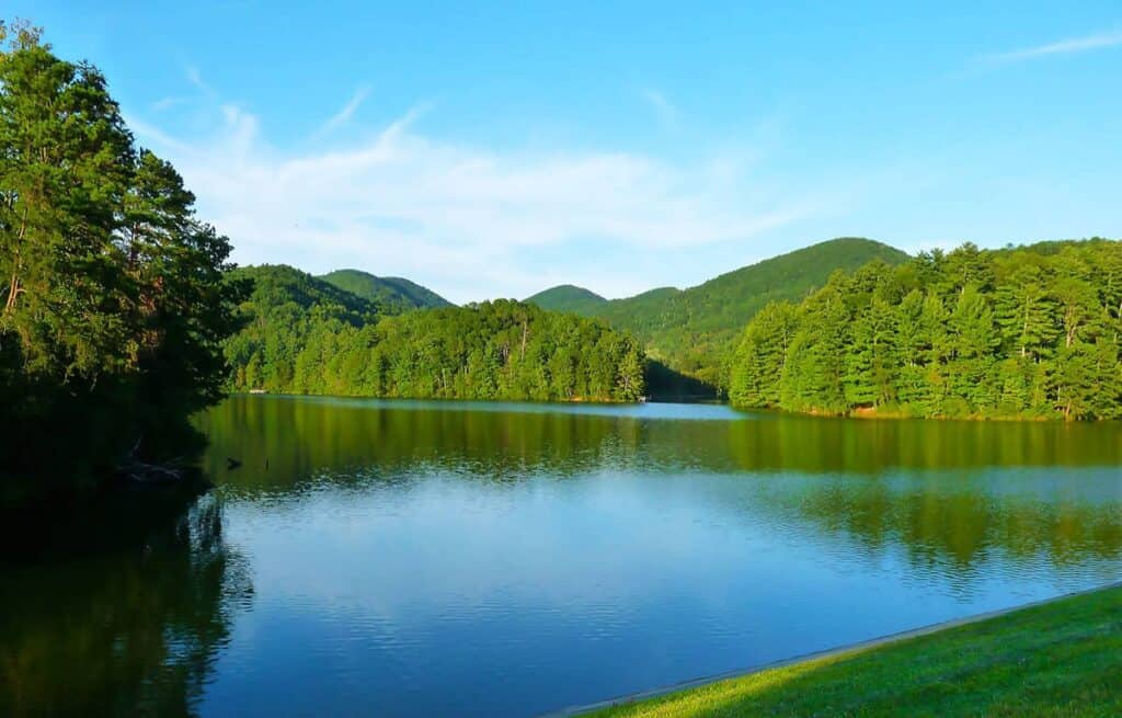Unicoi Lake with surrounding green hills and trees under a blue sky.