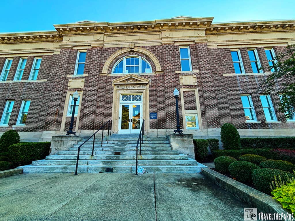 Front view of a brick Fort Monroe Visitor Center building with arched entrance and stone steps.

