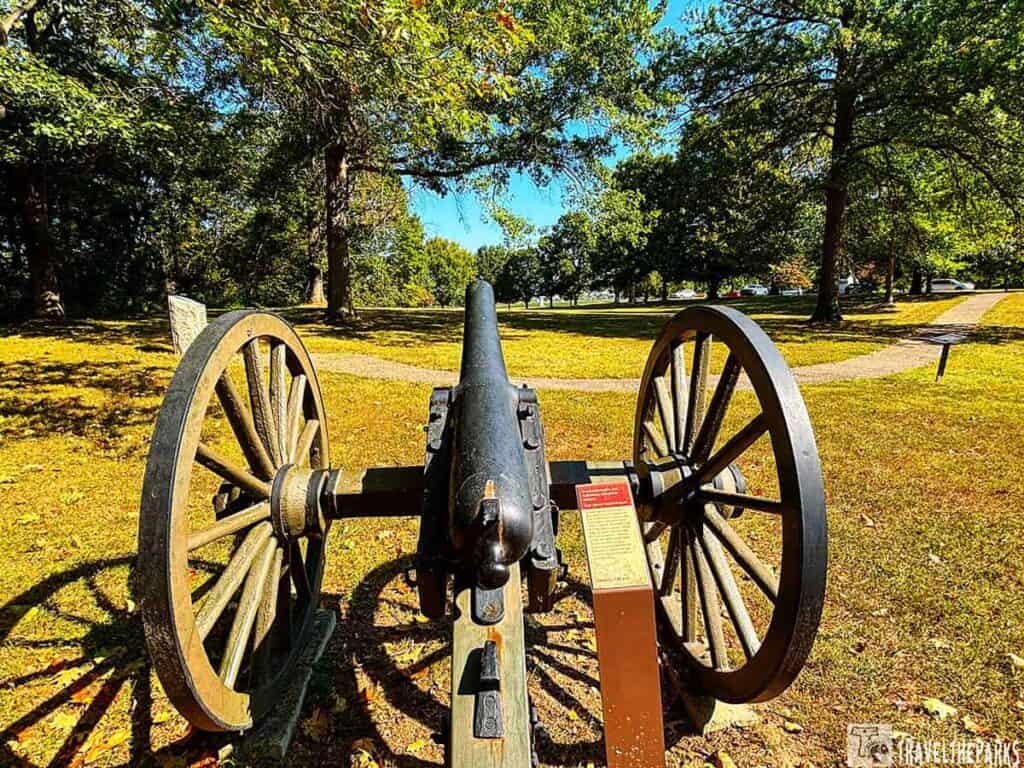 A historical cannon at the West Woods Antietam battlefield tour stop with trees and paths.