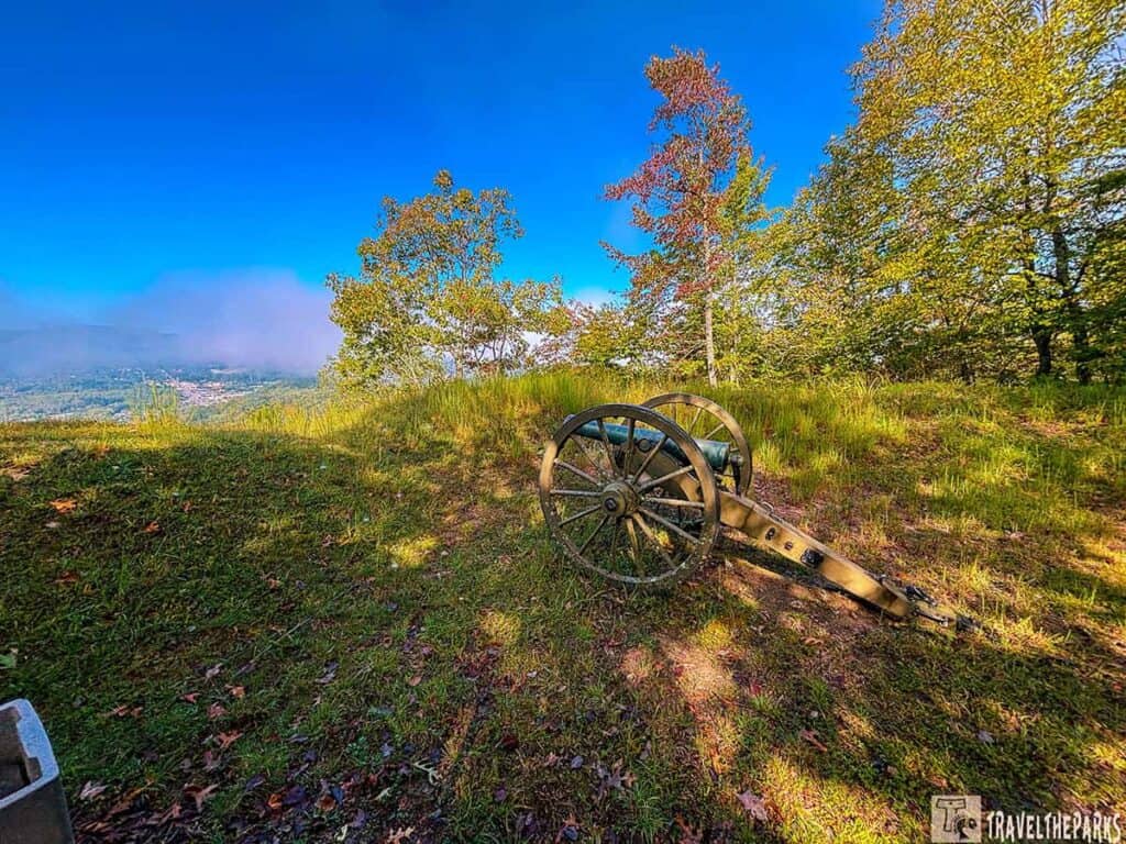 Object Lesson Road Cumberland Gap: Historic cannon on a grassy hill with trees and misty hills in the background.