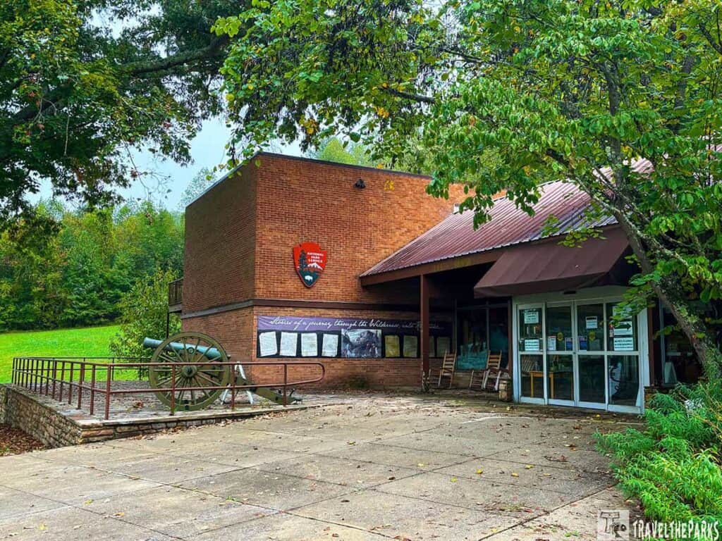 Visitor center at Cumberland Gap National Historical Park with a brick building, National Park Service emblem, a historic cannon, and surrounding greenery.