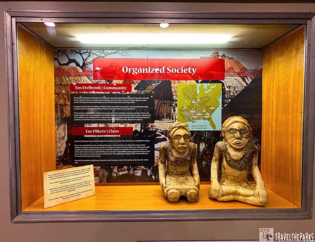 Museum display case featuring carved figures and an informational panel about Etowah Mounds.