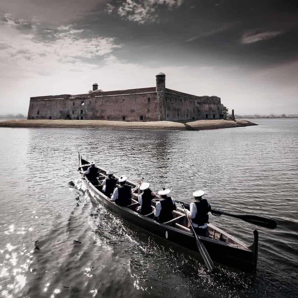 A boat of uniformed individuals rowing toward Fort Sumter on a cloudy day, early 1861.