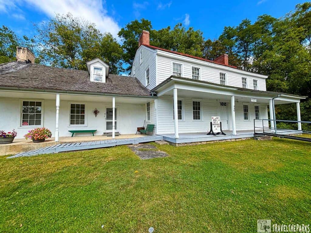 Historic Foster Armstrong House with porch and ramp, surrounded by grass and trees.