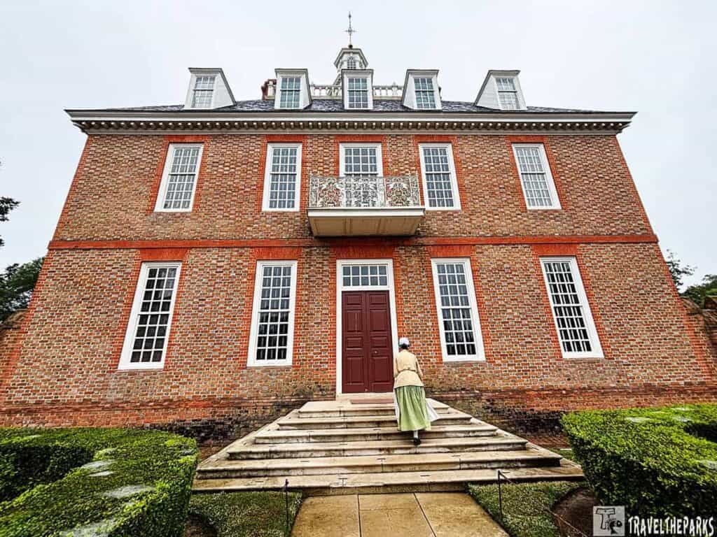 The Governor's Palace in Colonial Williamsburg with period-dressed figure climbing steps.