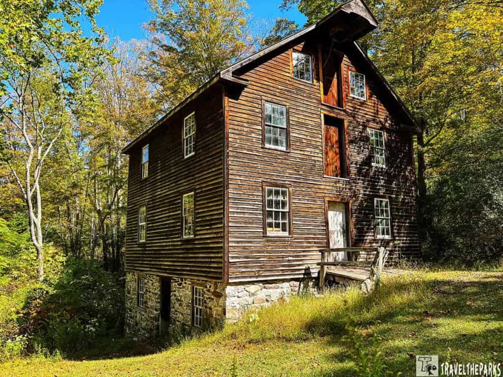A historic wooden grist mill in Millbrook Village, surrounded by autumn foliage.

