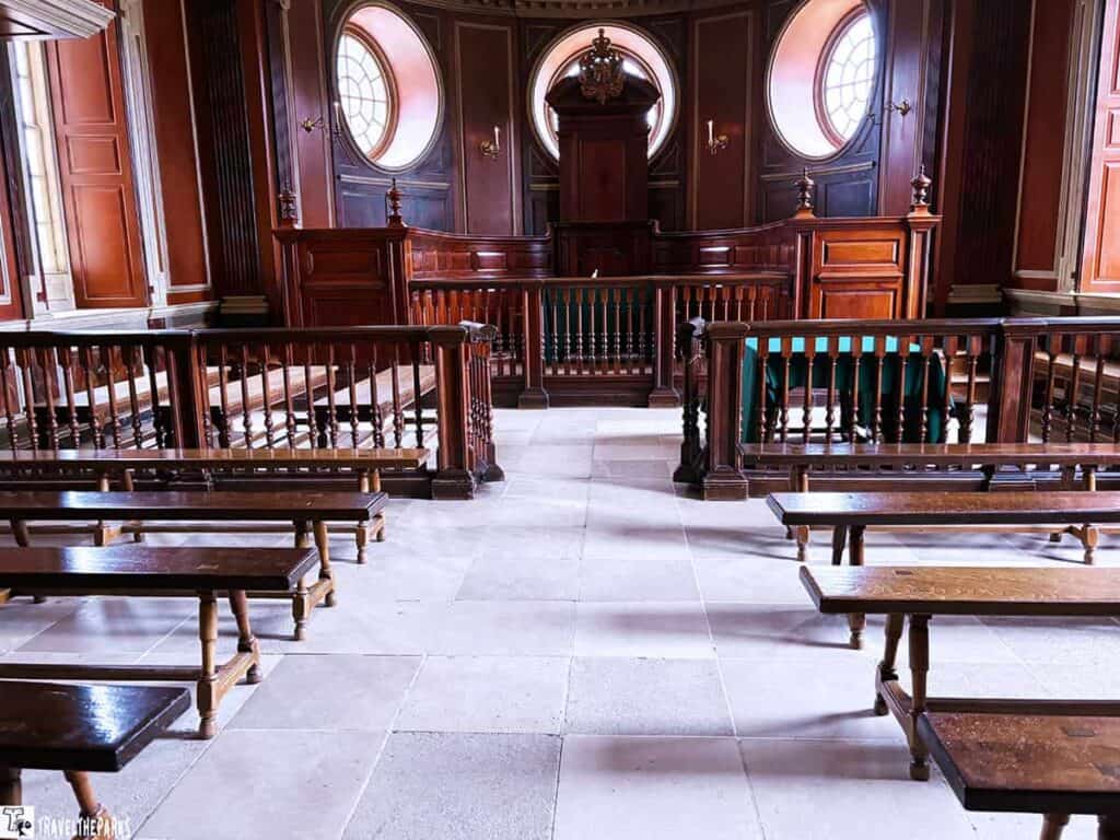 Historic chamber with wooden benches and a raised platform in a Capitol Building, Williamsburg.