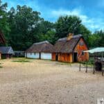 Historic Jamestown Settlement Fort James thatched-roof buildings and timber frames surround a sandy courtyard.