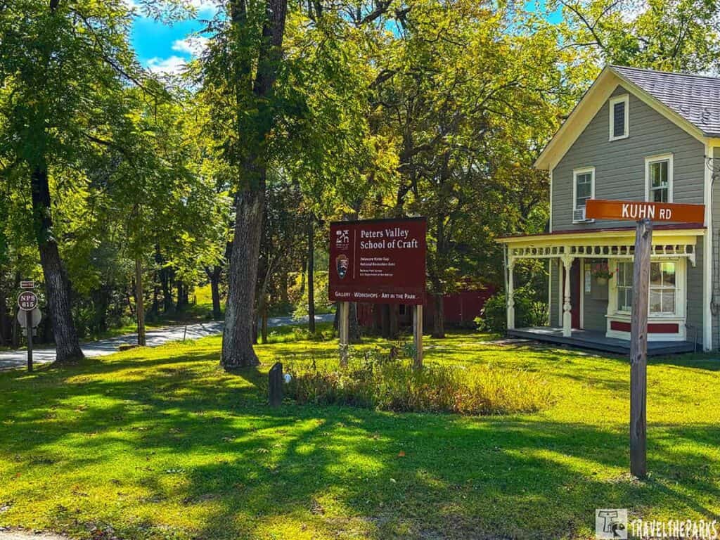 A house with a porch surrounded by trees and signs reading "Peters Valley School of Craft" and "KUHN RD."

