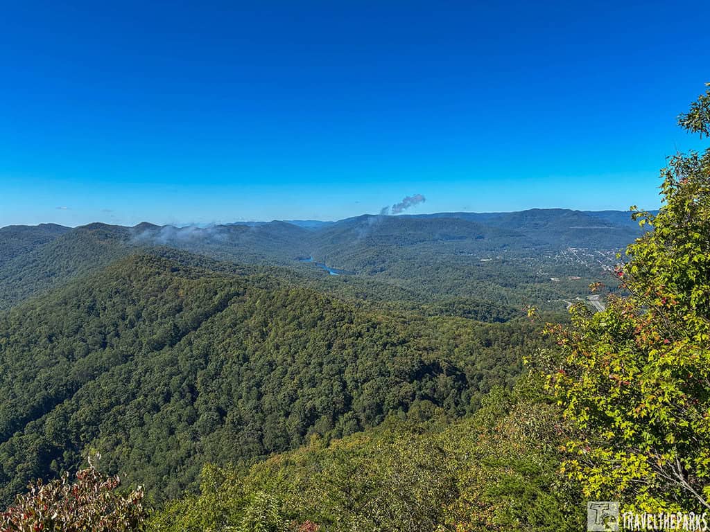 Cumberland Gap-Pinnacle Overlook-Panoramic view of a forested mountain range under a clear blue sky, with distant water reflections and hints of fall foliage.