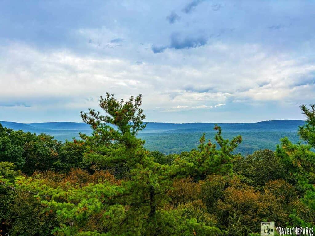 Scenic view from Pole Steeple Overlook with pine trees, forested hills, and a cloudy sky.