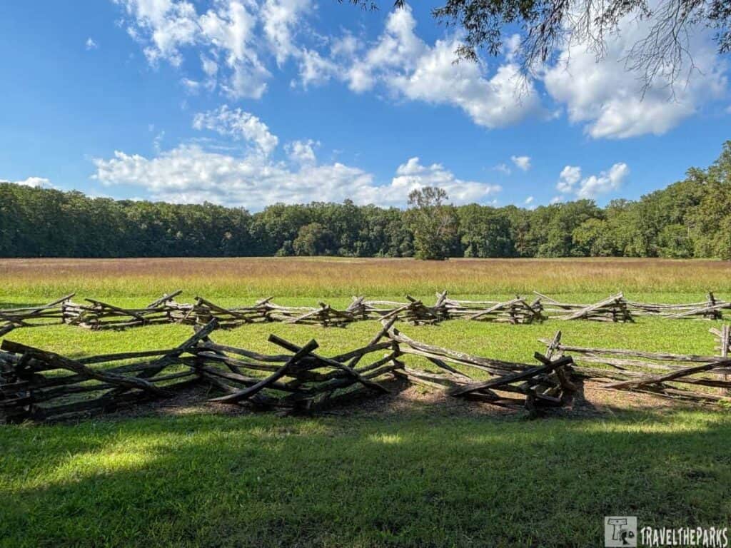 Zigzag wooden fence in a grassy field with trees and a blue sky in the background at Yorktown Battlefield.