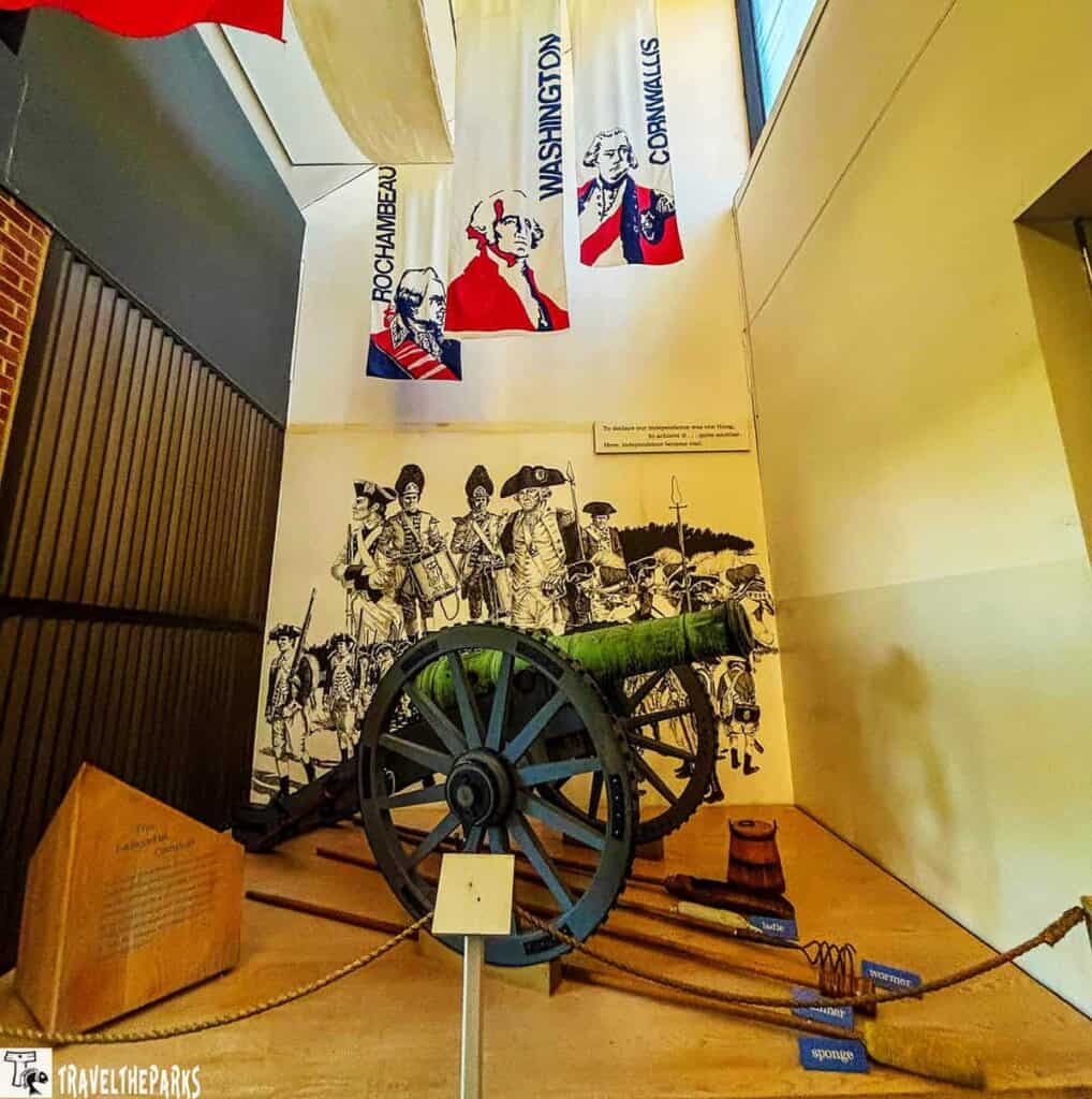 Lafayette Gun on display at Yorktown Battlefield, with historical mural and banners of Rochambeau, Washington, and Cornwallis.