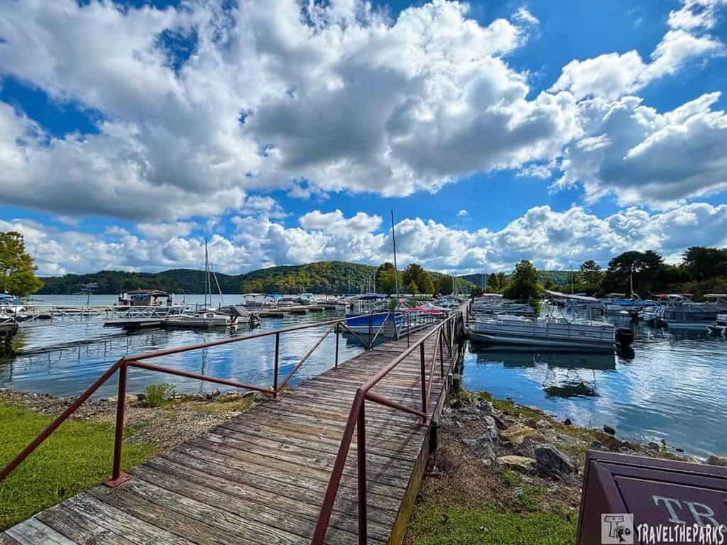 A marina at Calytor Lake State Park with boats docked by a wooden walkway, under a partly cloudy sky.

