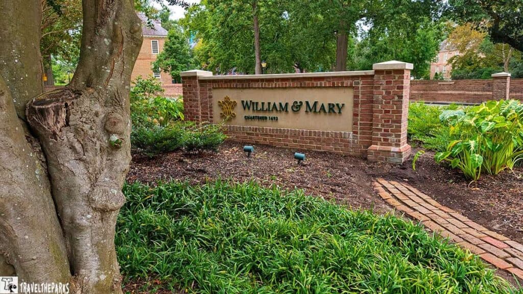 Brick sign for William & Mary surrounded by green plants and trees.
