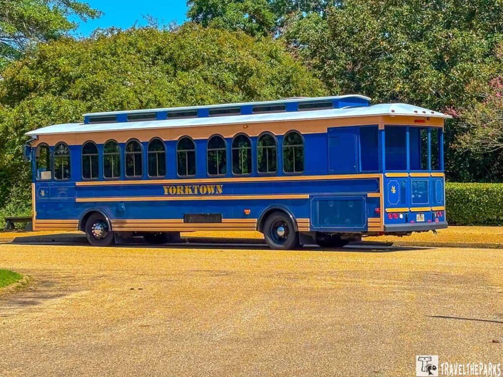 A blue and gold trolley labeled "YORKTOWN" parked in front of dense green foliage.