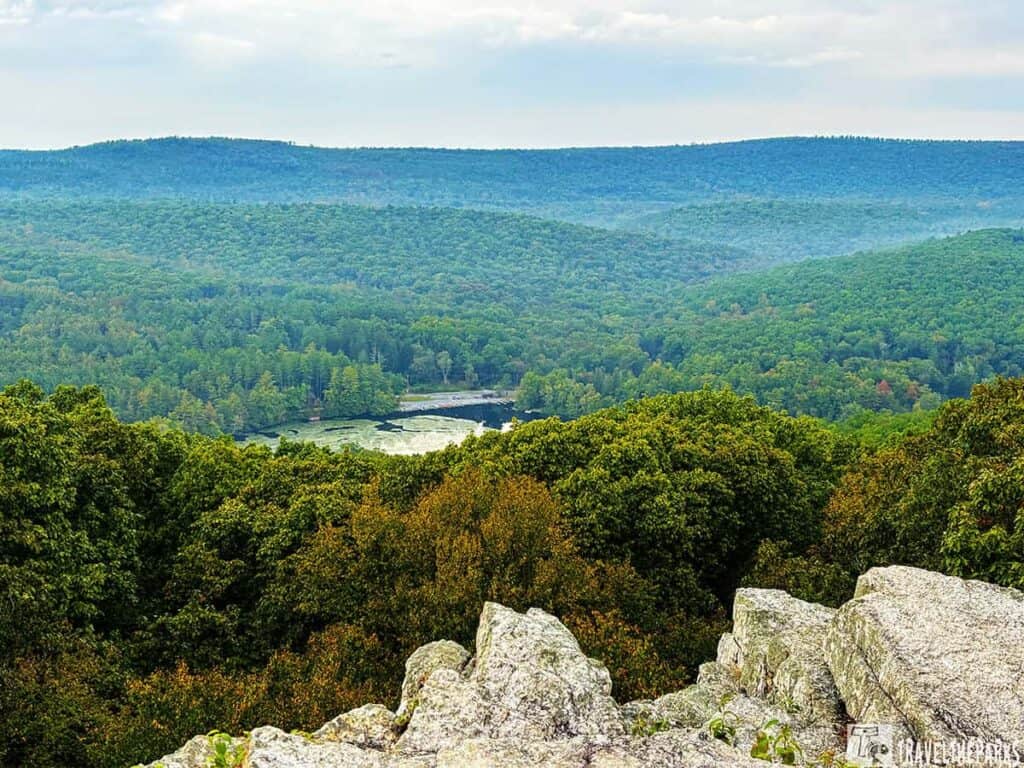 Panoramic view from Pole Steeple Trail showing rocky foreground and expansive forested landscape.