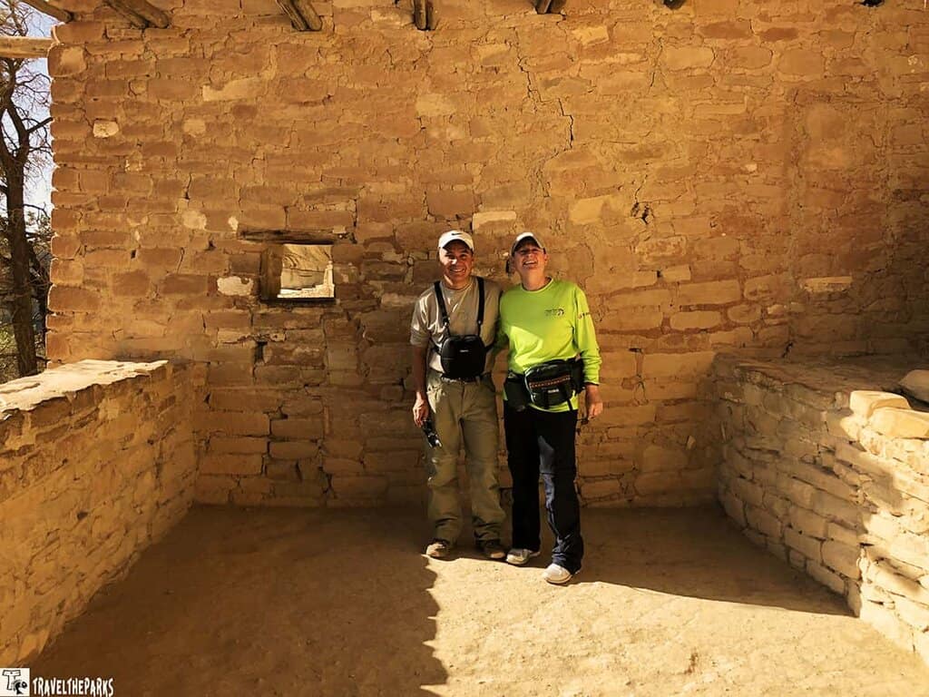 Two people standing inside a stone-walled room with a small window at Balcony House
