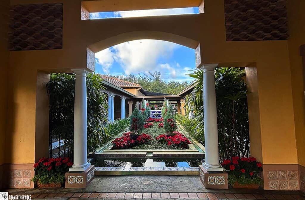 View of the garden courtyard at Bok Tower Gardens with white columns, a water feature, and vibrant plants.


