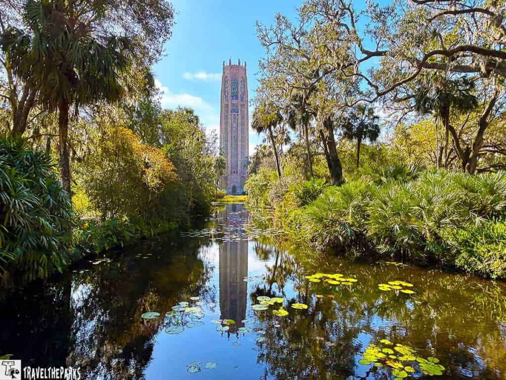 Bok Tower surrounded by lush greenery and a reflective pond with lily pads.

