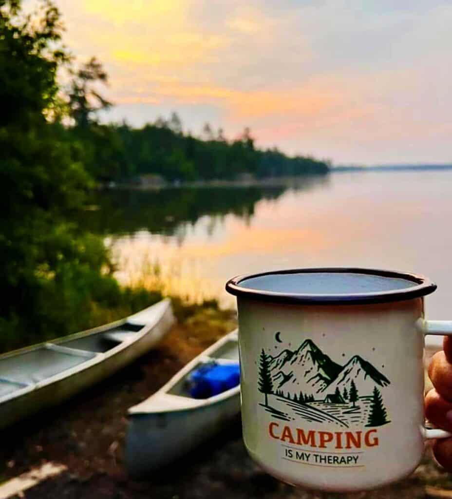 A campfire mug in front of the lake with canoes on the shoreline in Voyegeurs National Park