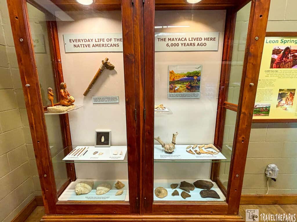 A wooden display case with Native American artifacts and informative labels.

