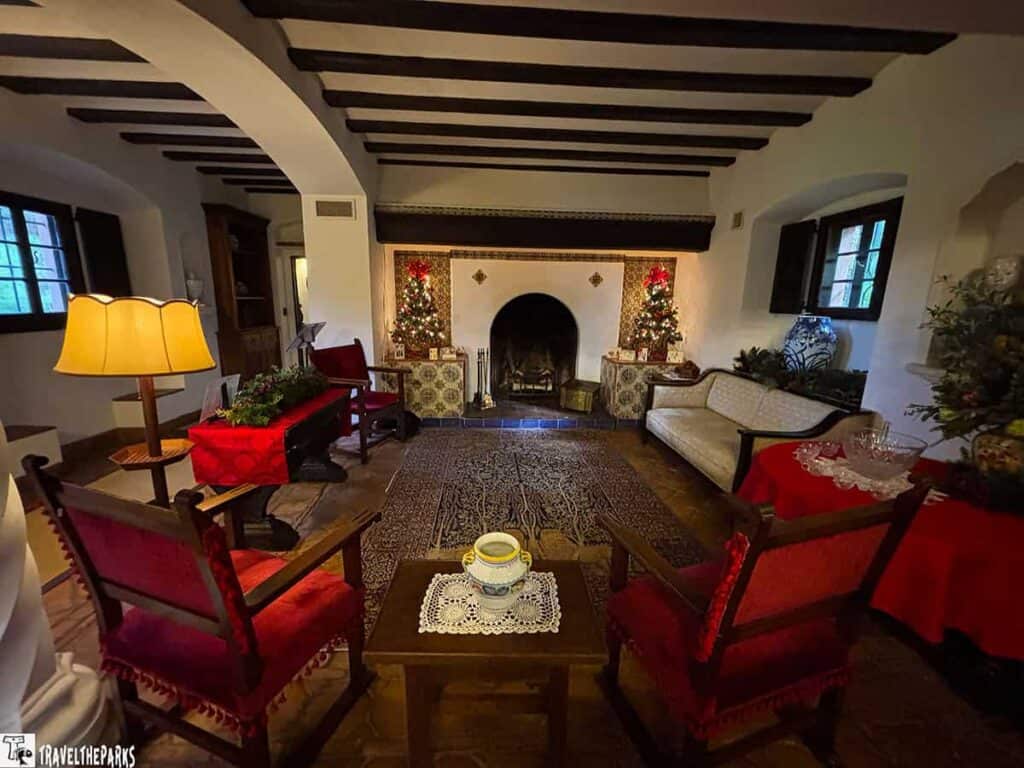 Cozy living room with fireplace, Christmas trees, and rustic decor in El Retiro mansion.

