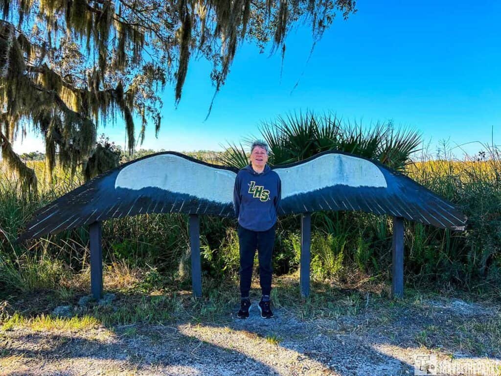 Person standing in front of large stylized bird wings at Lake Woodruff NWR.