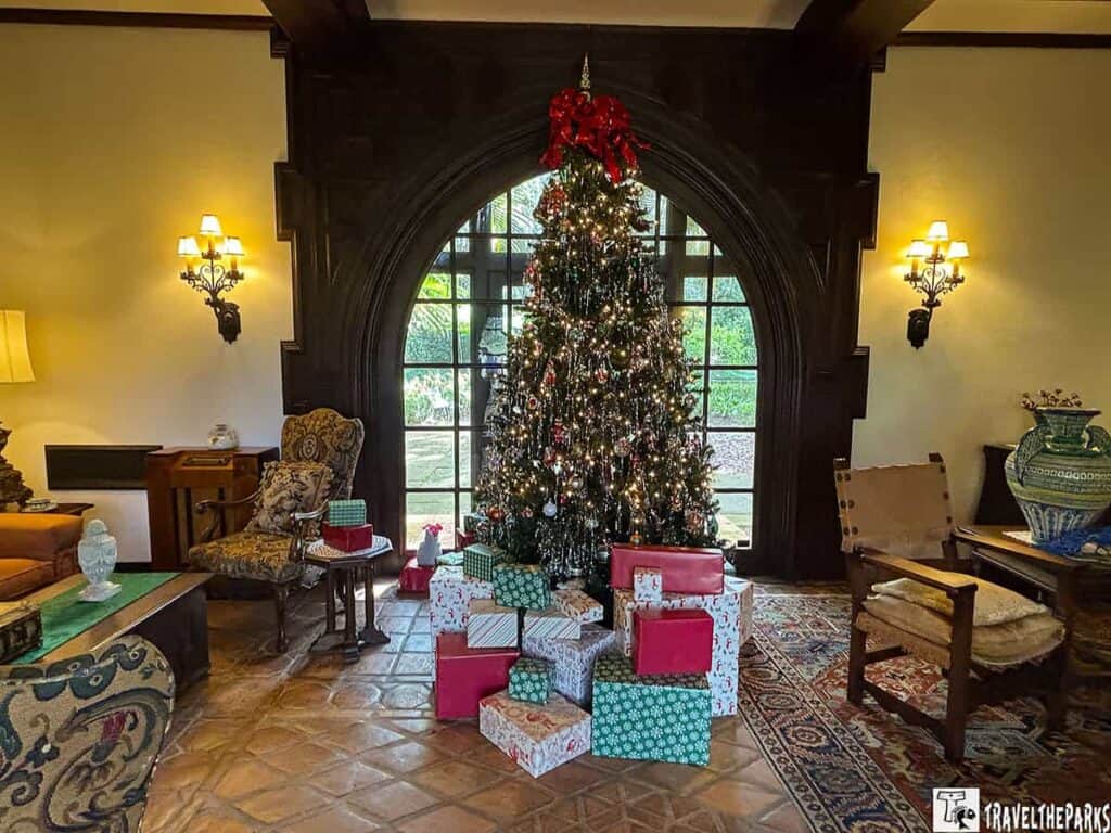 Interior room with a decorated Christmas tree and wrapped gifts near a large arched window.


