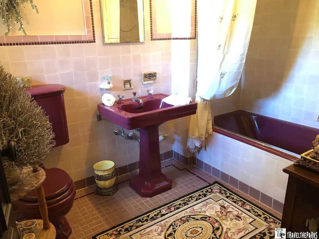 Vintage bathroom with burgundy fixtures and peach tiles.

