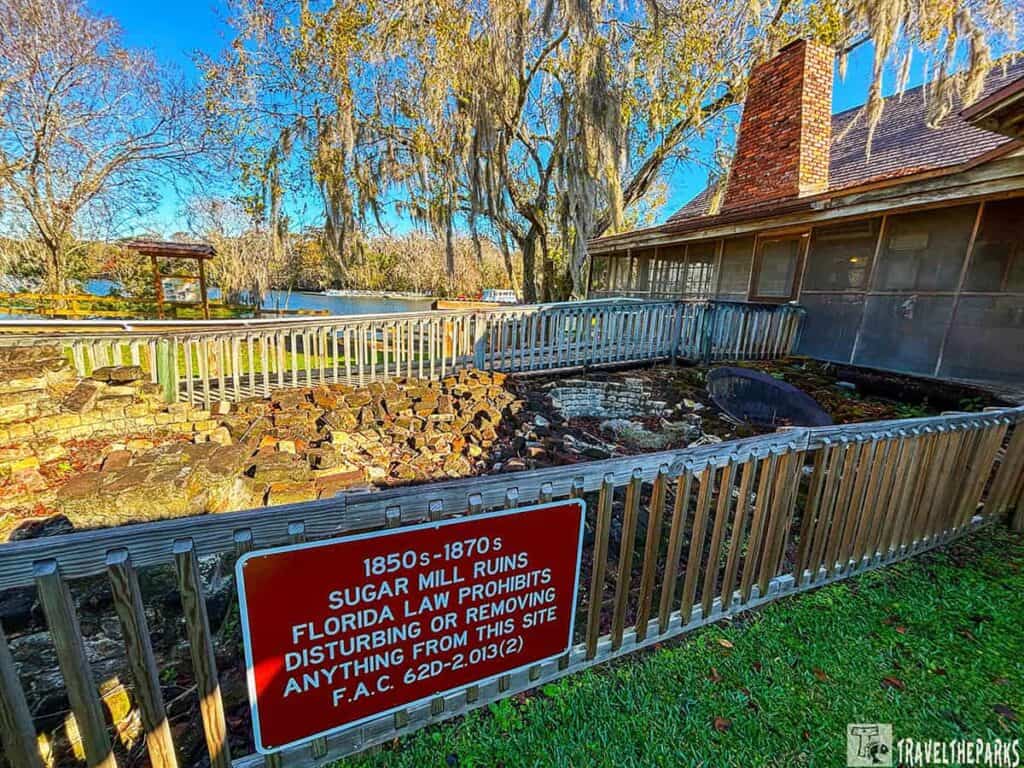 Sugar mill ruins at Deleon Springs State Park with an informational sign and building in the background.

