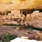 Ancient cliff dwelling structures at Long House in Mesa Verde with stone walls, ladders, and doorways.