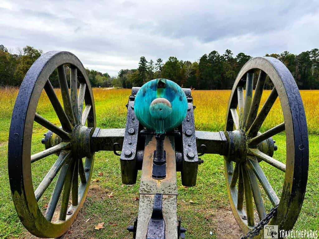 Antique cannon with large wheels on a grassy field, background of tall grass and trees. Chickamauga Battlefield Tour, Chickamauga and Chattanooga National Military Park