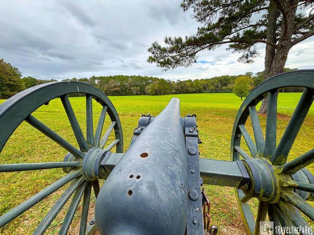 Cannon on Viniard Field, Chickamauga Battlefield, with wheels on either side, aiming towards a grassy field and distant trees.

