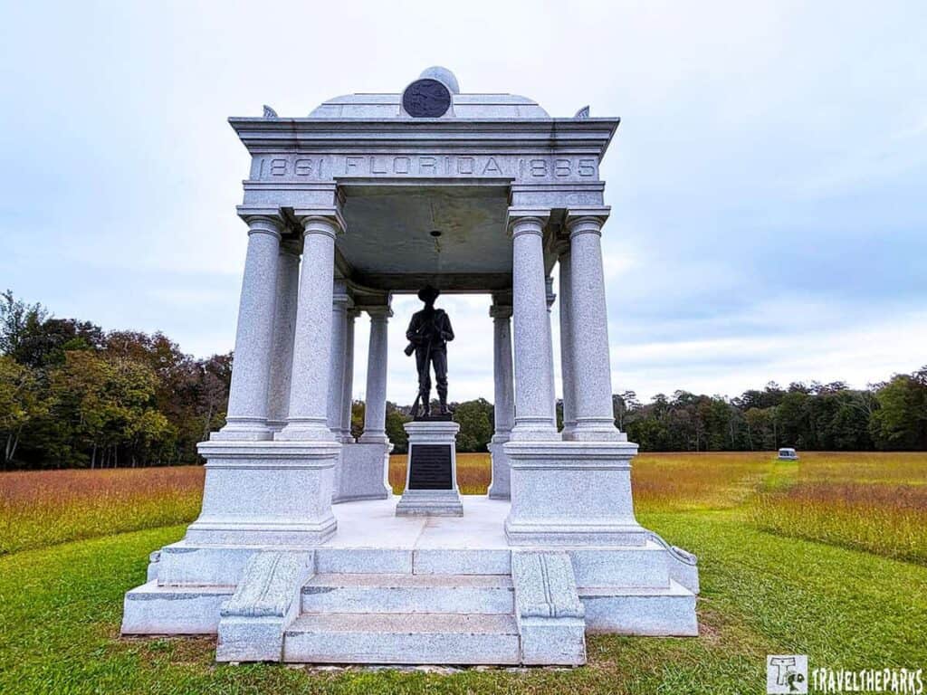 Stone monument with columns and a soldier statue in a field. Florida Monument in the Chickamauga  Battlefield 

