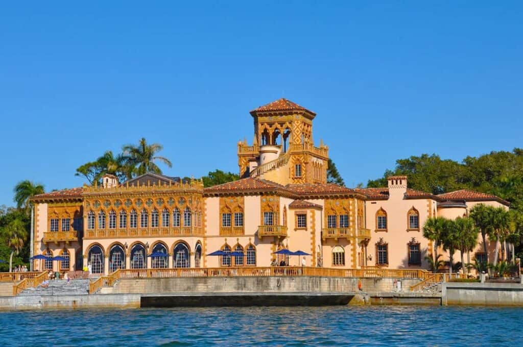 Ca’ d’Zan Mediterranean-style mansion with pink stucco walls, a central tower, and a terrace by the water. At the Ringling Museum.

