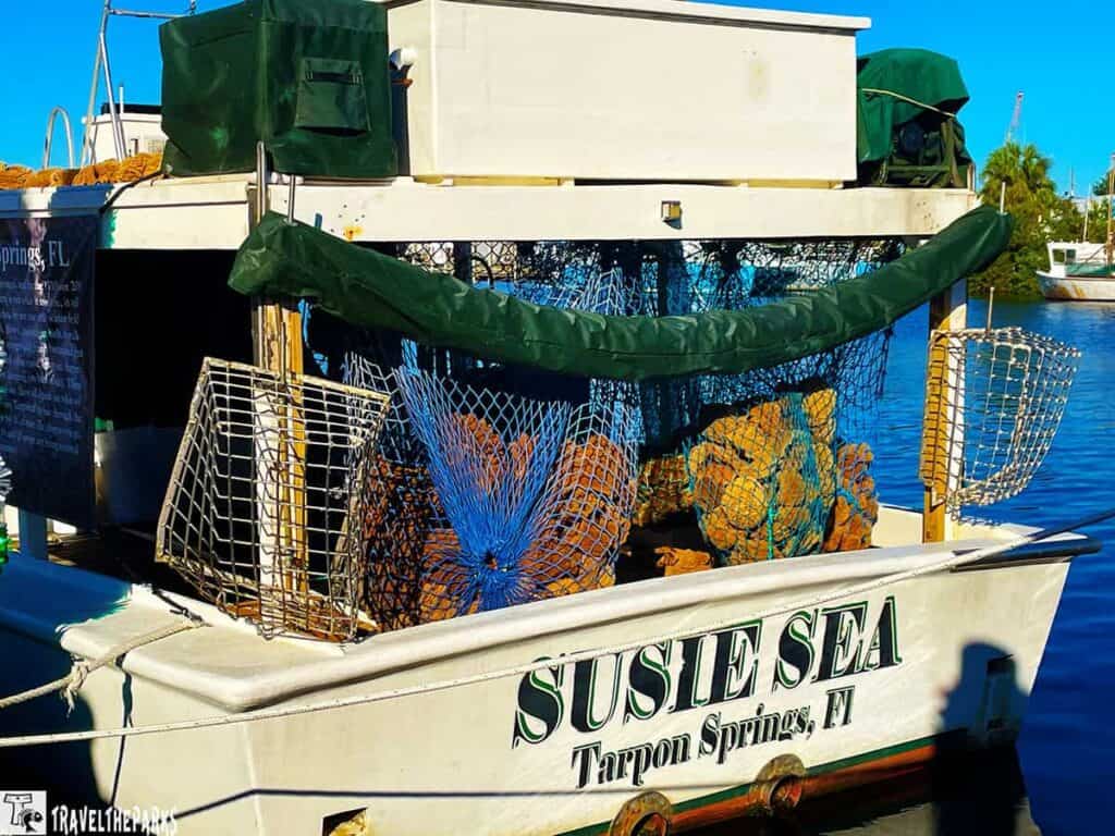 A small fishing boat named "SUSIE SEA" with nets and traps on the deck, docked in a marina under a blue sky.

