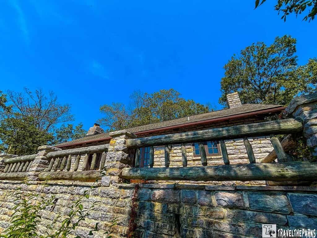 Stone building with a wooden railing and chimney under a clear blue sky.