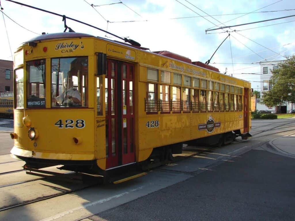 A yellow vintage streetcar numbered 428 with red accents on tracks in an urban setting.

