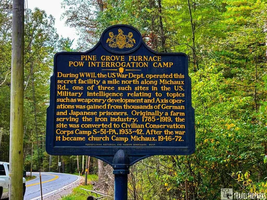Historical marker for Pine Grove Furnace POW Interrogation Camp in a wooded area.