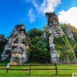 Tall limestone rock formations at Natural Chimneys Park with a bright blue sky and green foliage.