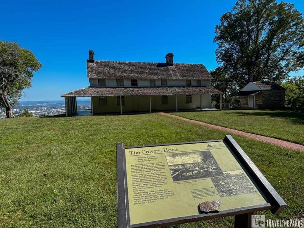 Cravens House: Two-story house with a sloped roof, a lawn in the foreground, and a sign in front. A smaller stone structure is to the right.