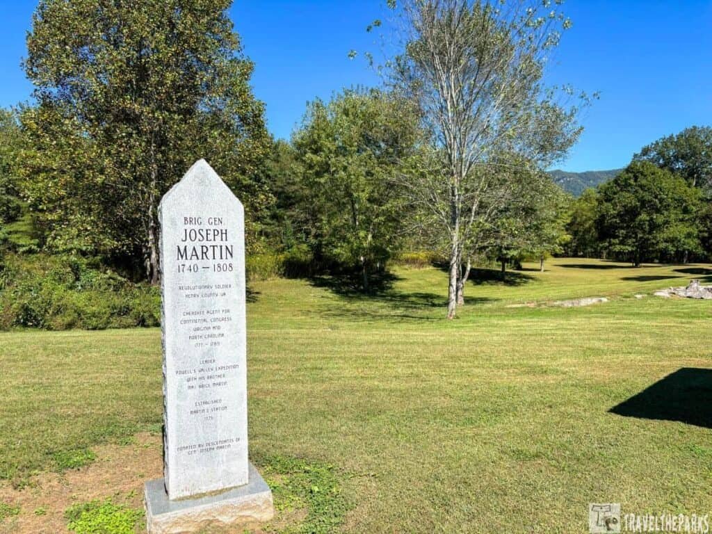 Stone marker for Brig. Gen. Joseph Martin on a grassy field with trees and mountains in the background.