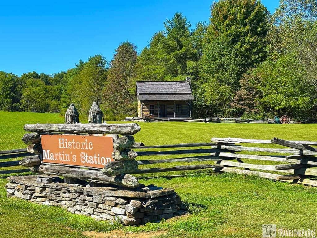 A log cabin at Historic Martin's Station, with a wooden sign and fence in the foreground.