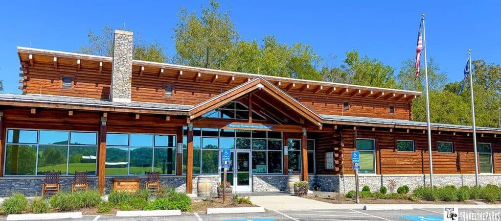 Visitor center at Wilderness Road State Park with a log cabin design, stone chimney, and two flags.