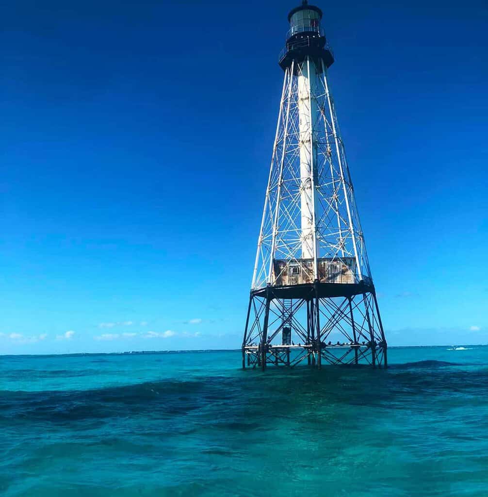 Alligator Reef Lighthouse in turquoise ocean under a clear blue sky.