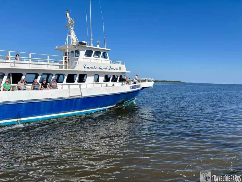 A ferry named "Cumberland Queen II" on a body of water with passengers onboard under a clear blue sky.

