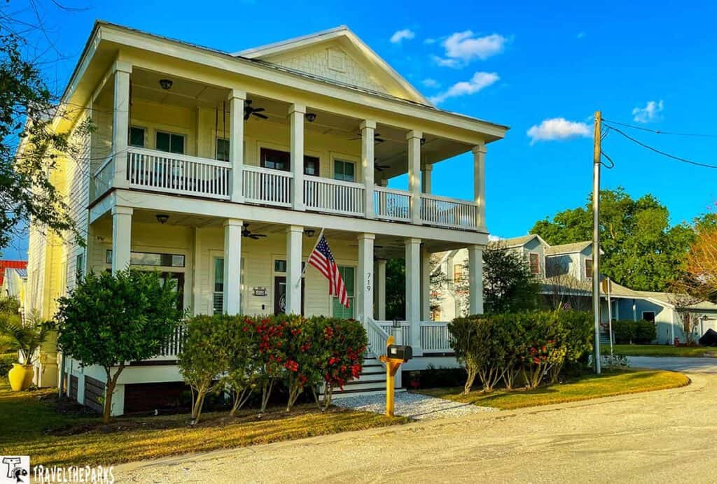 Fernindina Beach two-story yellow Victorian house with porches, columns, and an American flag out front.

